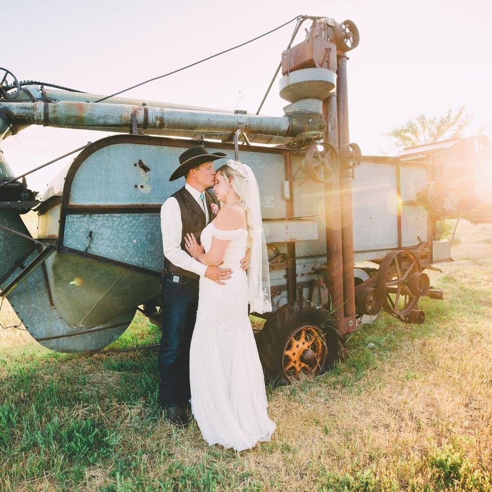 Bride and groom pose in front of tractor in Wyoming