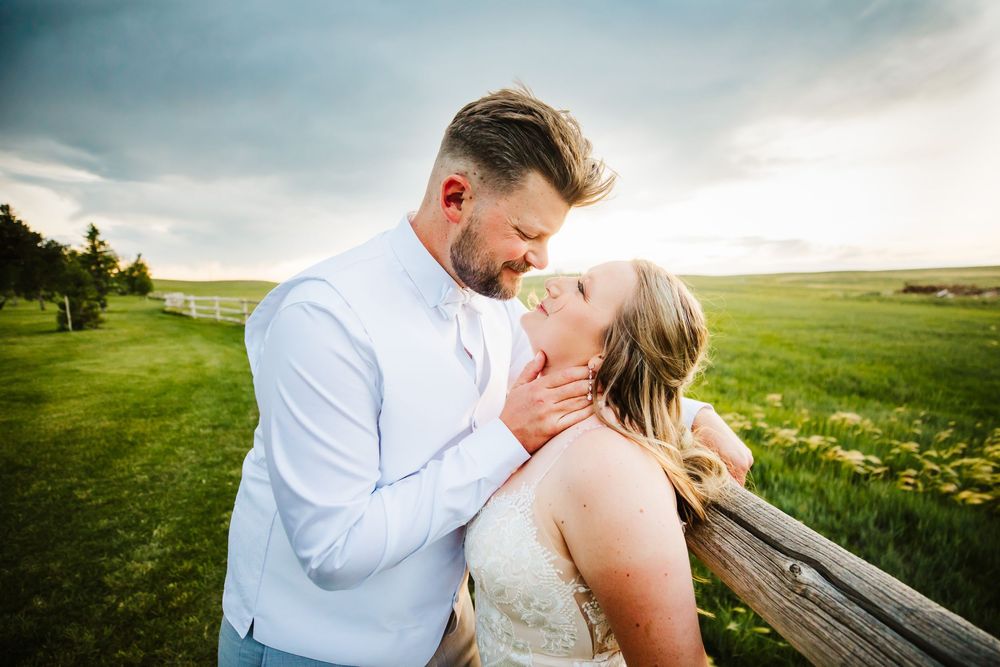 Newly married bride and groom in green field with cloudy sky in Cheyenne, WY