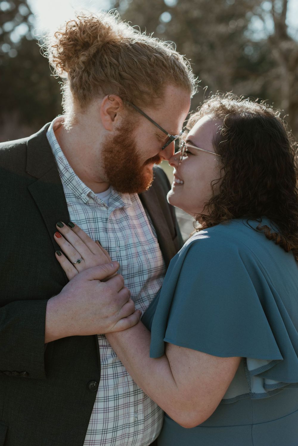 Intimate couple sharing a tender moment during an outdoor engagement session.