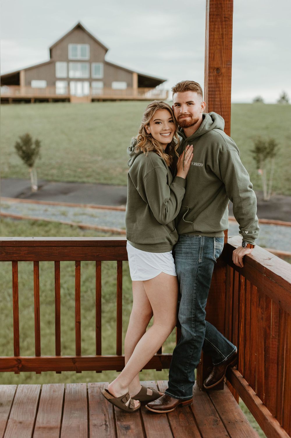 Couple sharing intimate moments on rustic wooden porch with mountain house in background.
