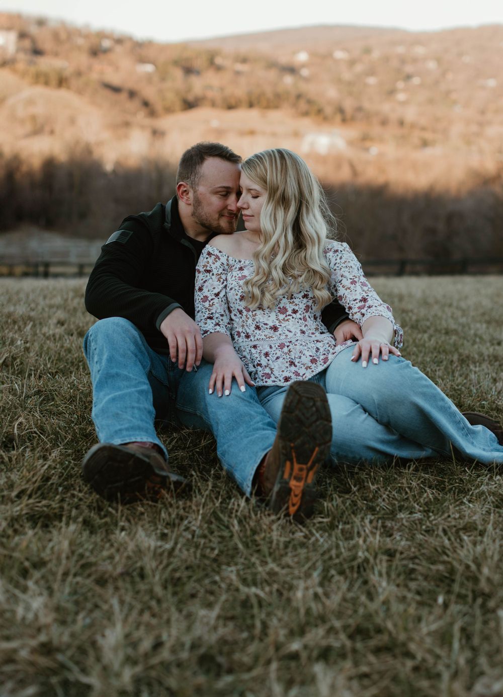 Intimate couple photoshoot in a grassy field during golden hour.