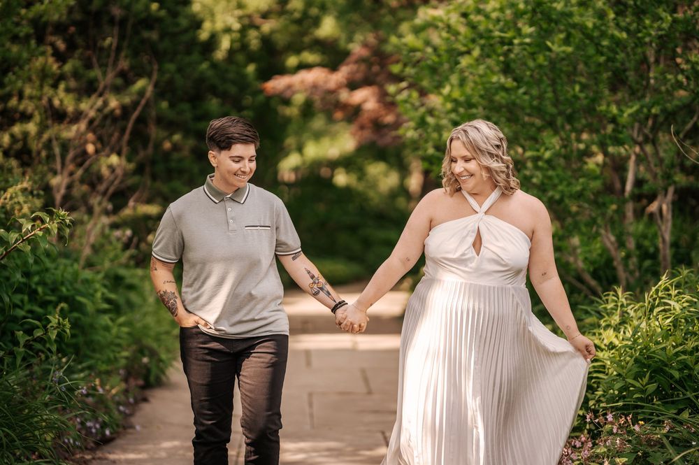 A couple poses together in a lush garden setting during a romantic outdoor photoshoot.