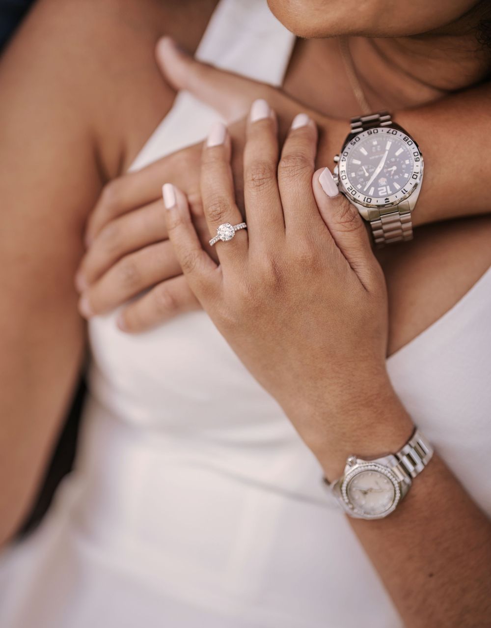 Close-up view of a sparkling diamond engagement ring being shown on a hand against a light background.