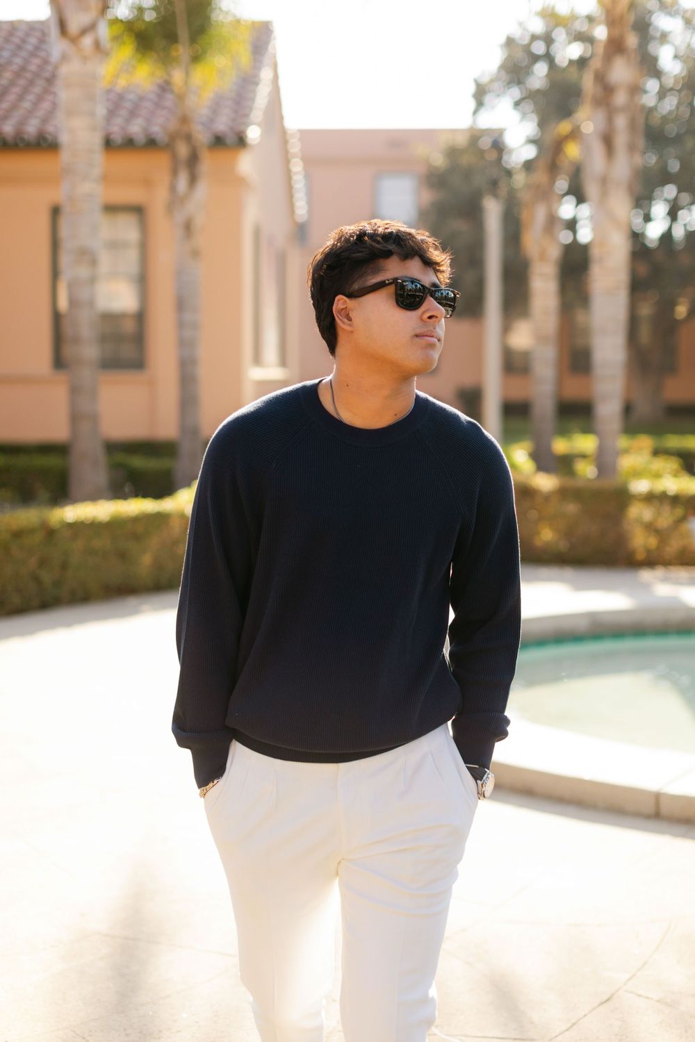 A fashion photography sequence showing a person in a black sweater and white pants posing in natural sunlight.