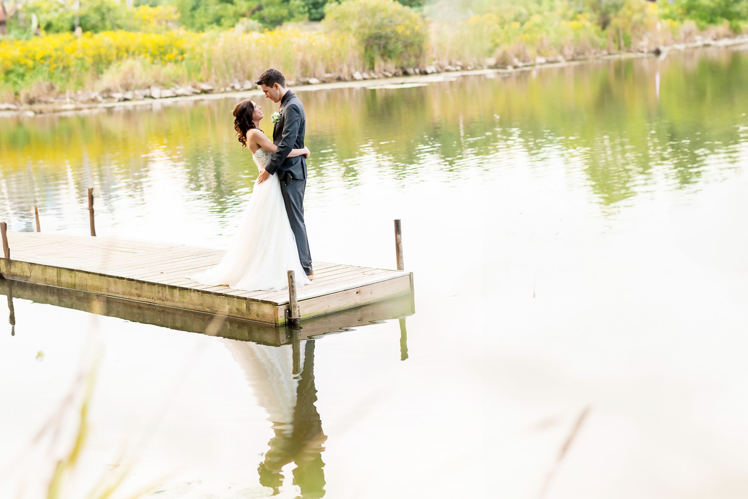 Couple poses for romantic photos on a wooden dock by a serene lake at Springwater Conservation Area.