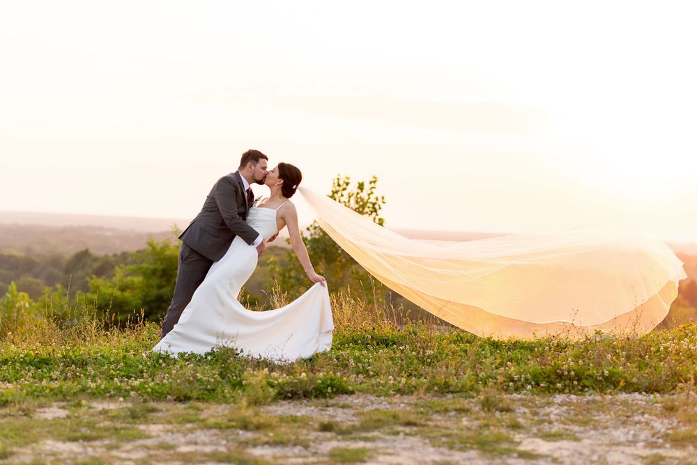 Romantic wedding photo series with a flowing veil at sunset in a meadow.