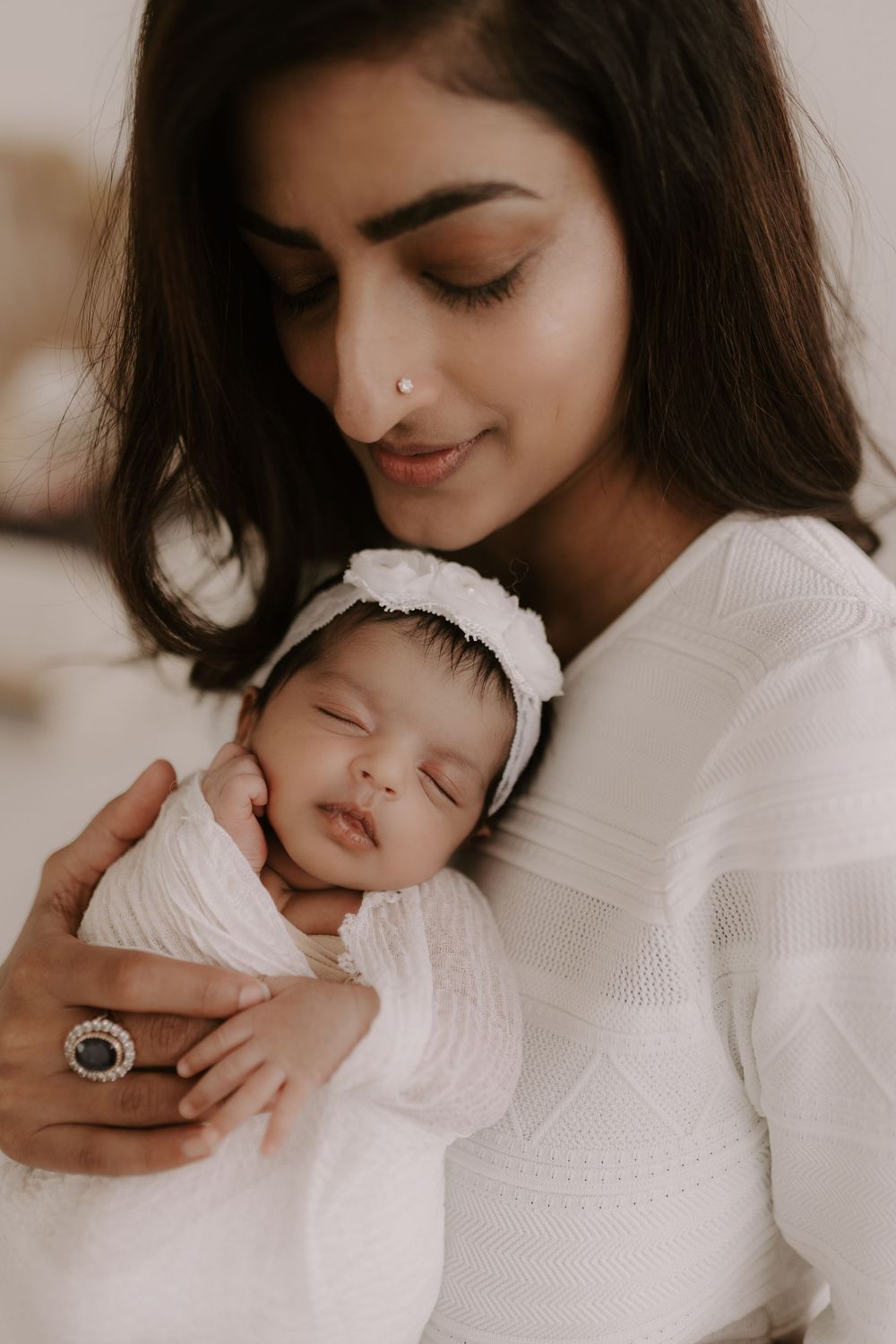 Minimalist white studio portraits showing tender moments with a sleeping newborn.