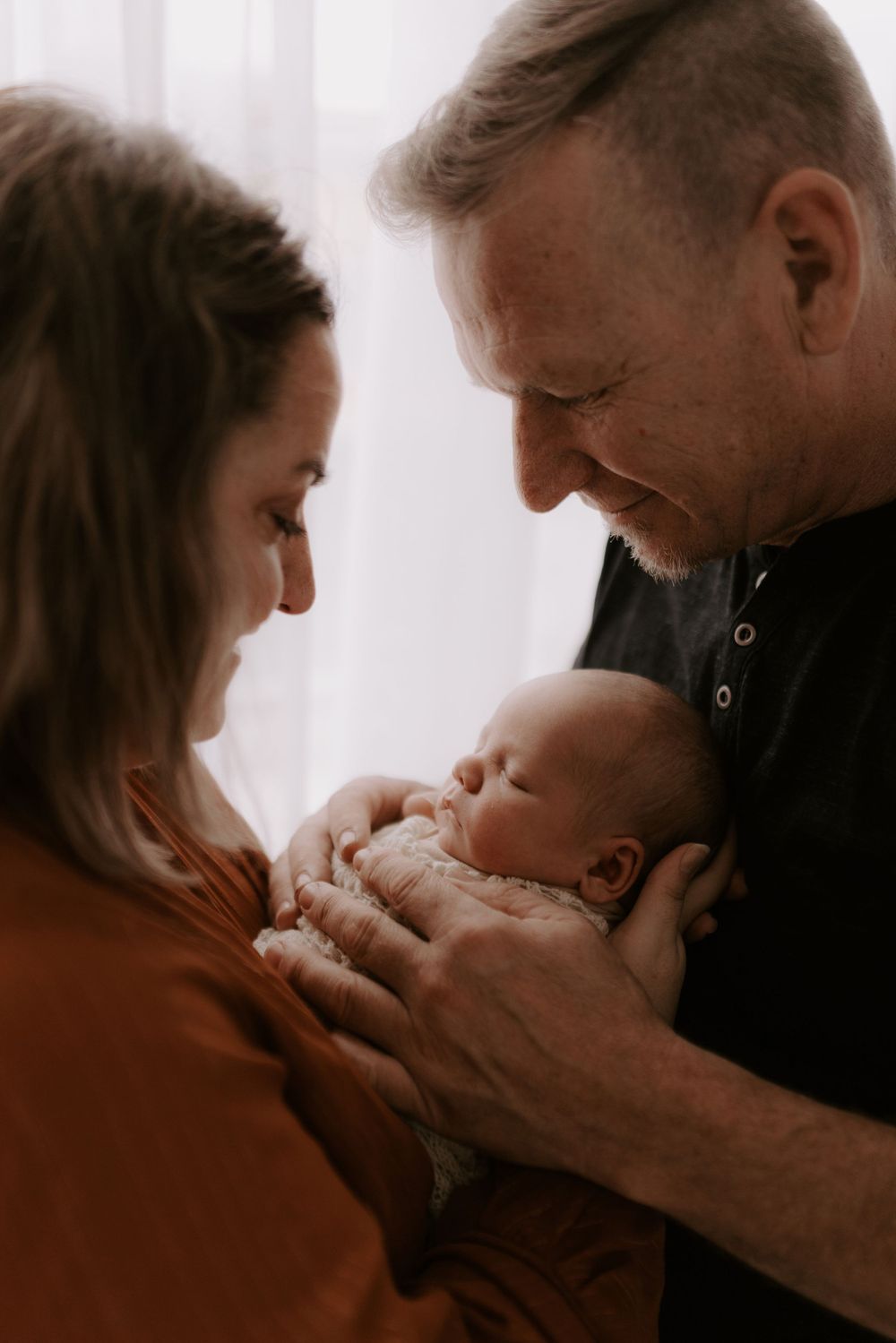 Warm sepia-toned family portraits showing tender moments with newborn.