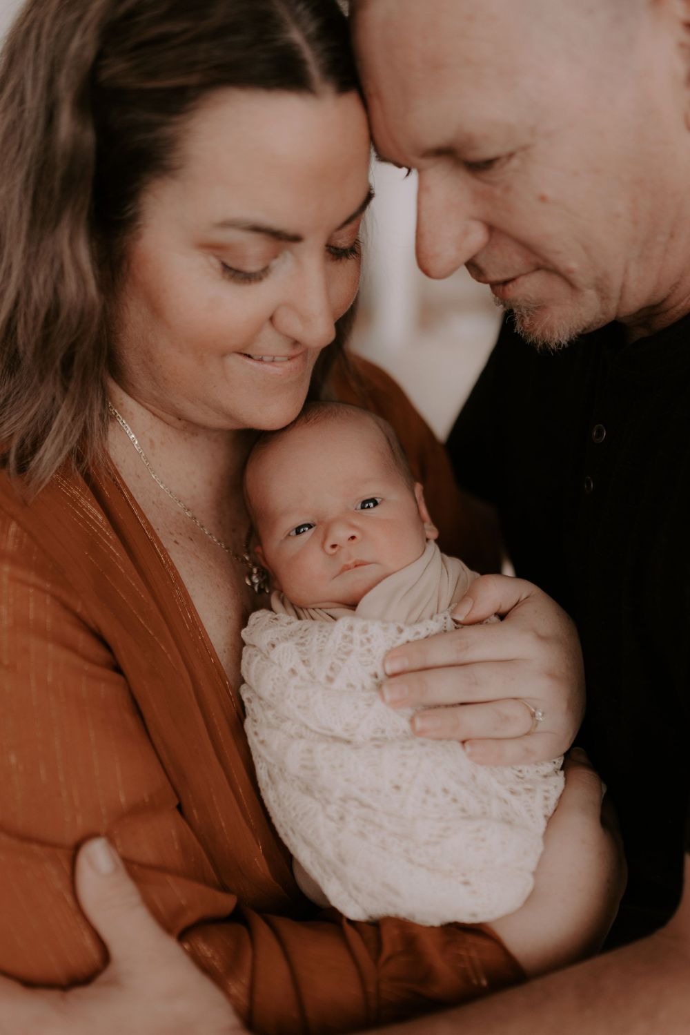 Family portrait series in warm tones showing intimate moments with sleeping baby.