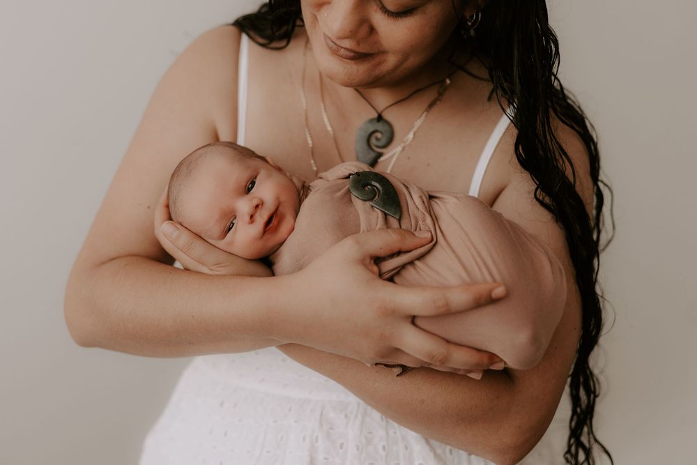 Intimate newborn photography session with soft natural lighting and neutral background.