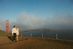 Engaged couple walking along the San Francisco coastline near the Golden Gate Bridge during a romantic film photography session