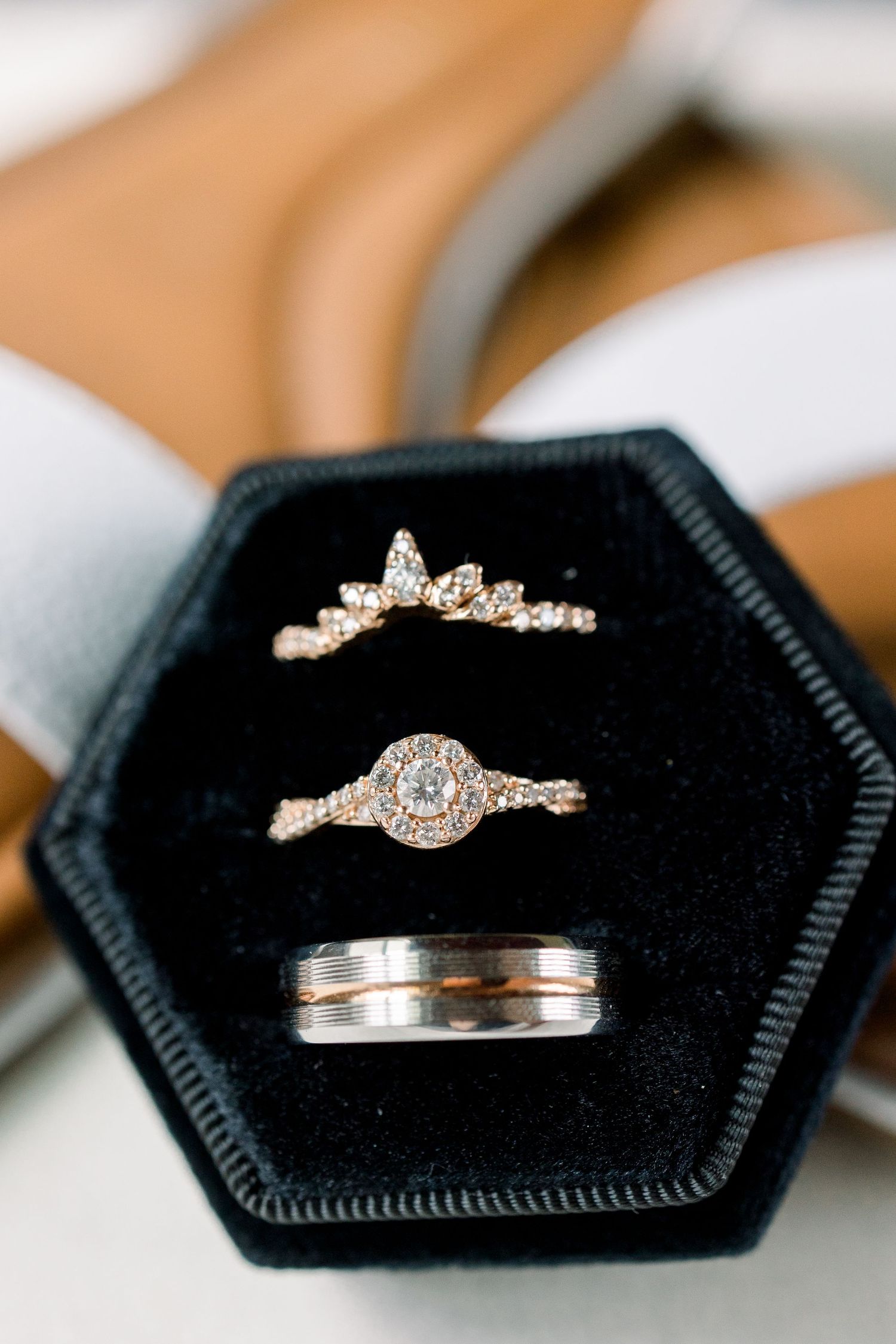 Wedding rings displayed on black velvet hexagonal ring boxes showing various elegant diamond designs.