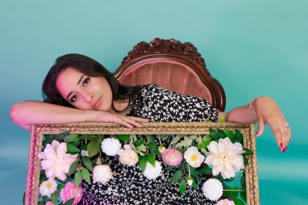 Portrait photography: studio portrait of a woman leaning her head against a large frame covered in flowers
