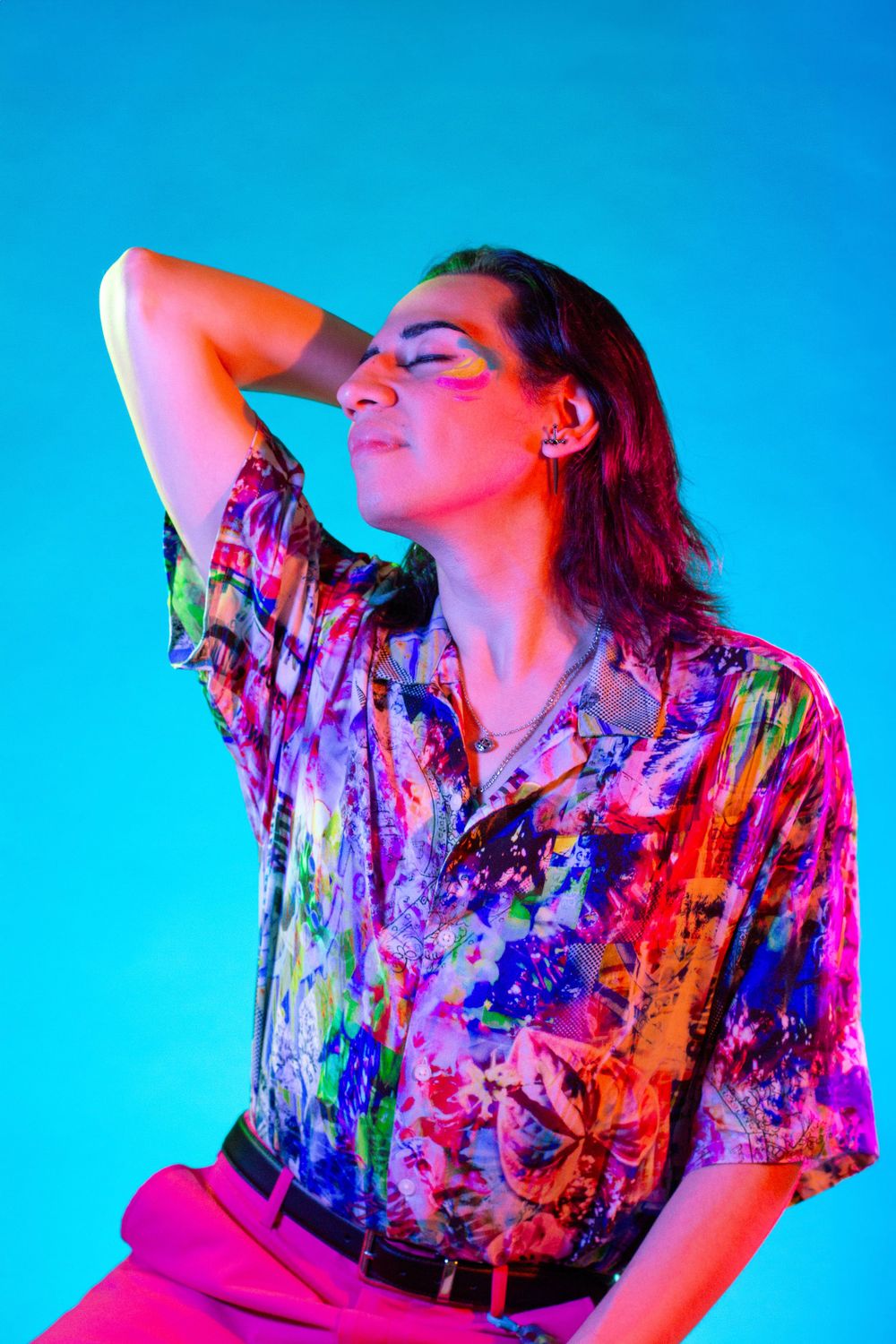 Portrait photography:  a man wearing a muticolored shirt and makeup surrounded by blue, green, and red light