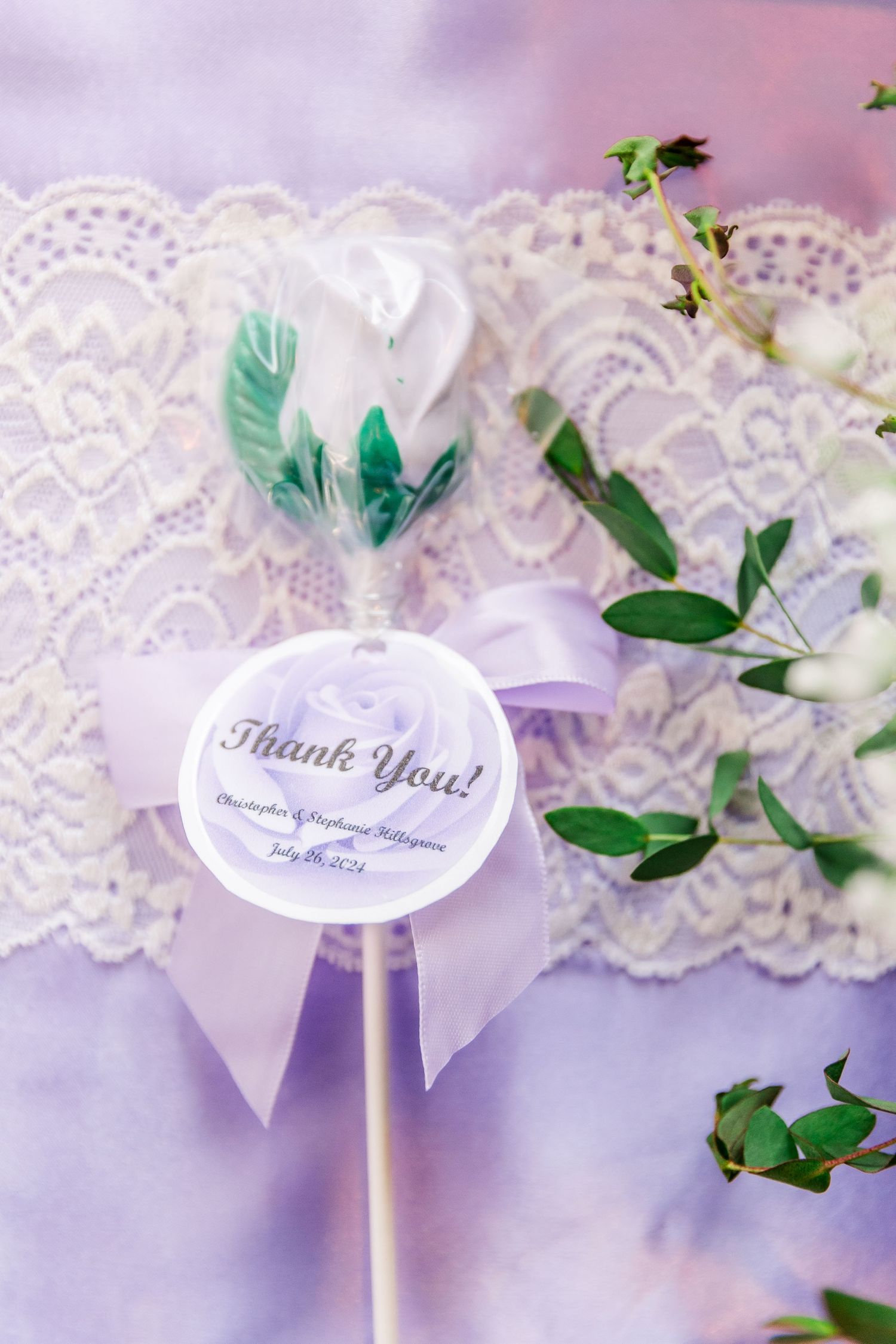 A decorative 'Thank You' sign with feathers and lace details in soft purple and mint tones.