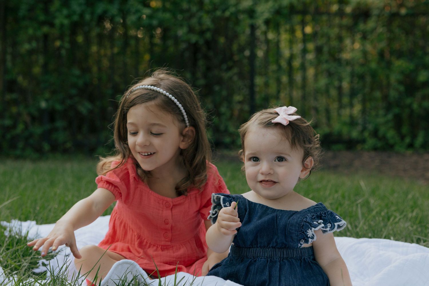 Two children laughing while sitting on a blanket during an outdoor photo session.