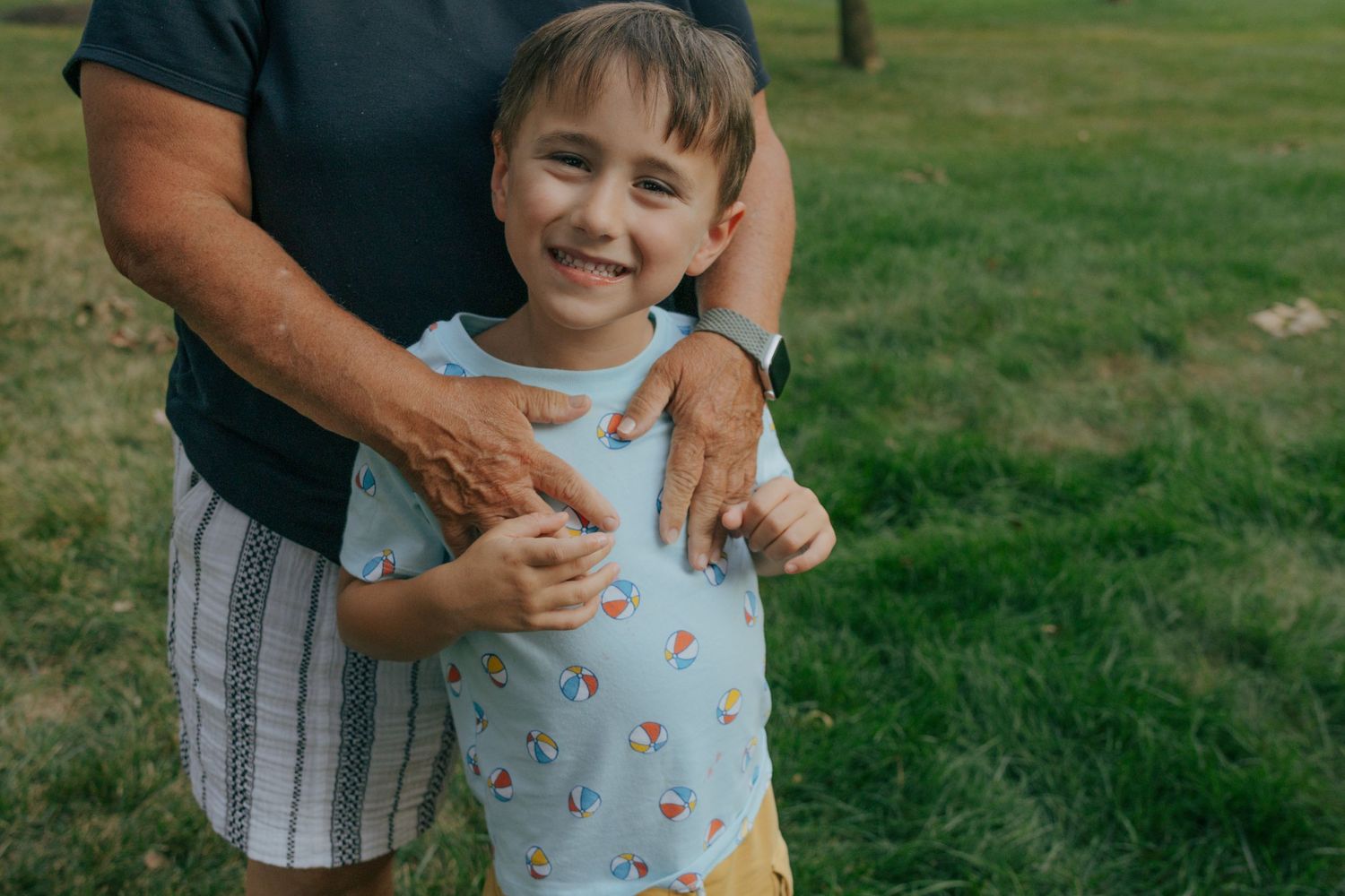 Child in floral outfit smiling during outdoor summer photoshoot.