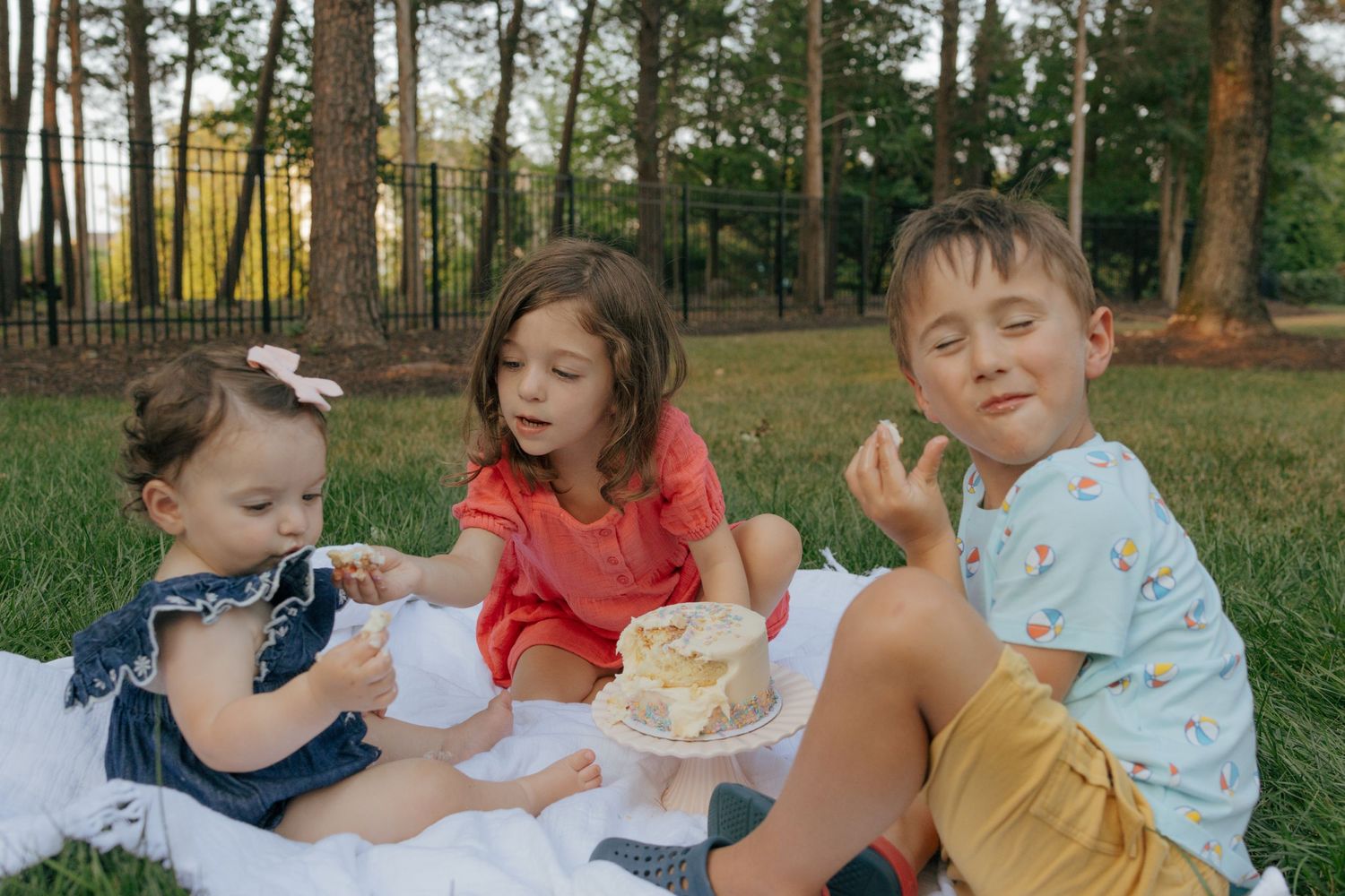 Kids sharing food and laughing during an outdoor picnic gathering.