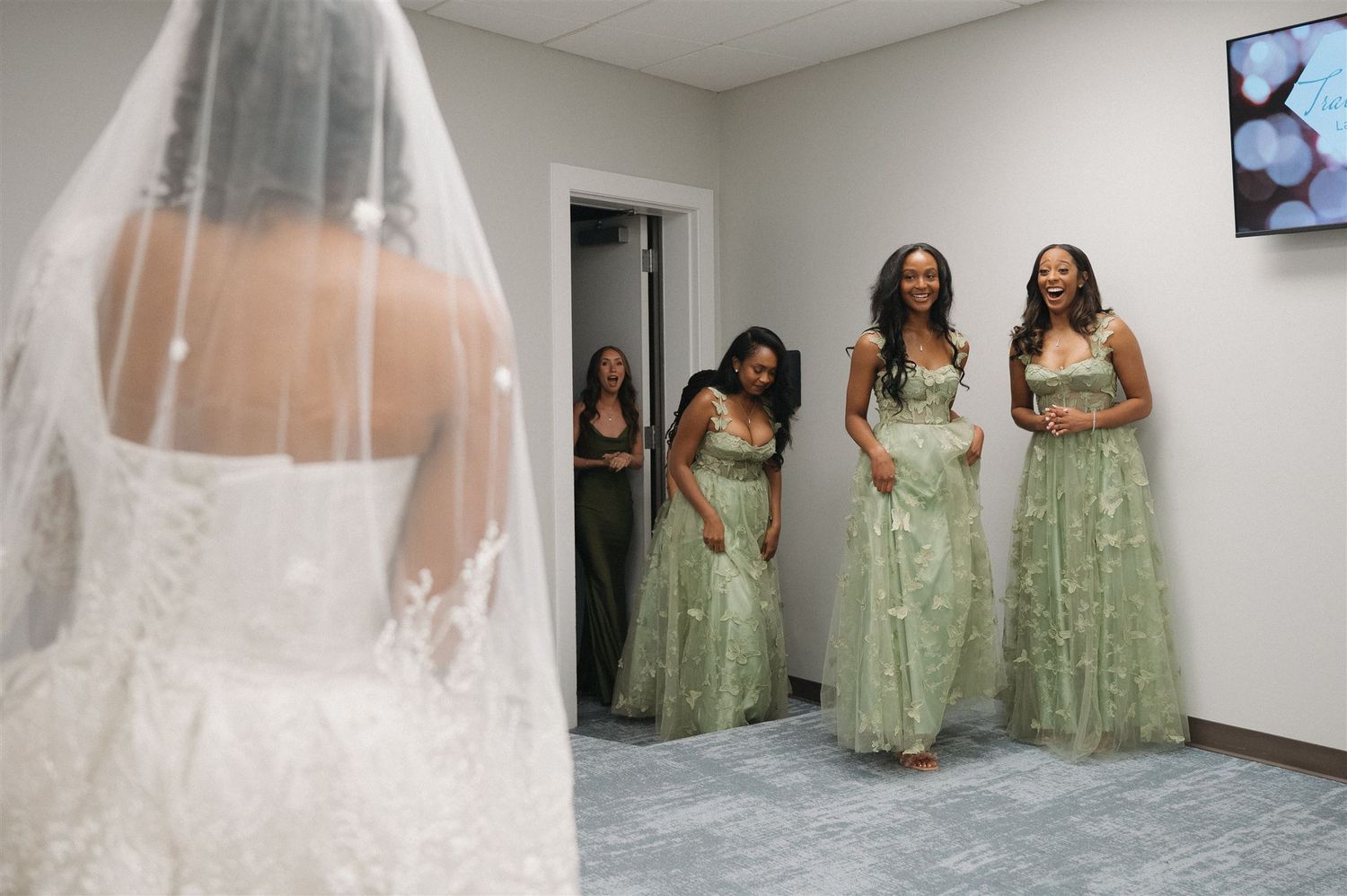 Bridesmaids in mint green dresses watch the bride with her veil in a bridal suite before the ceremony.