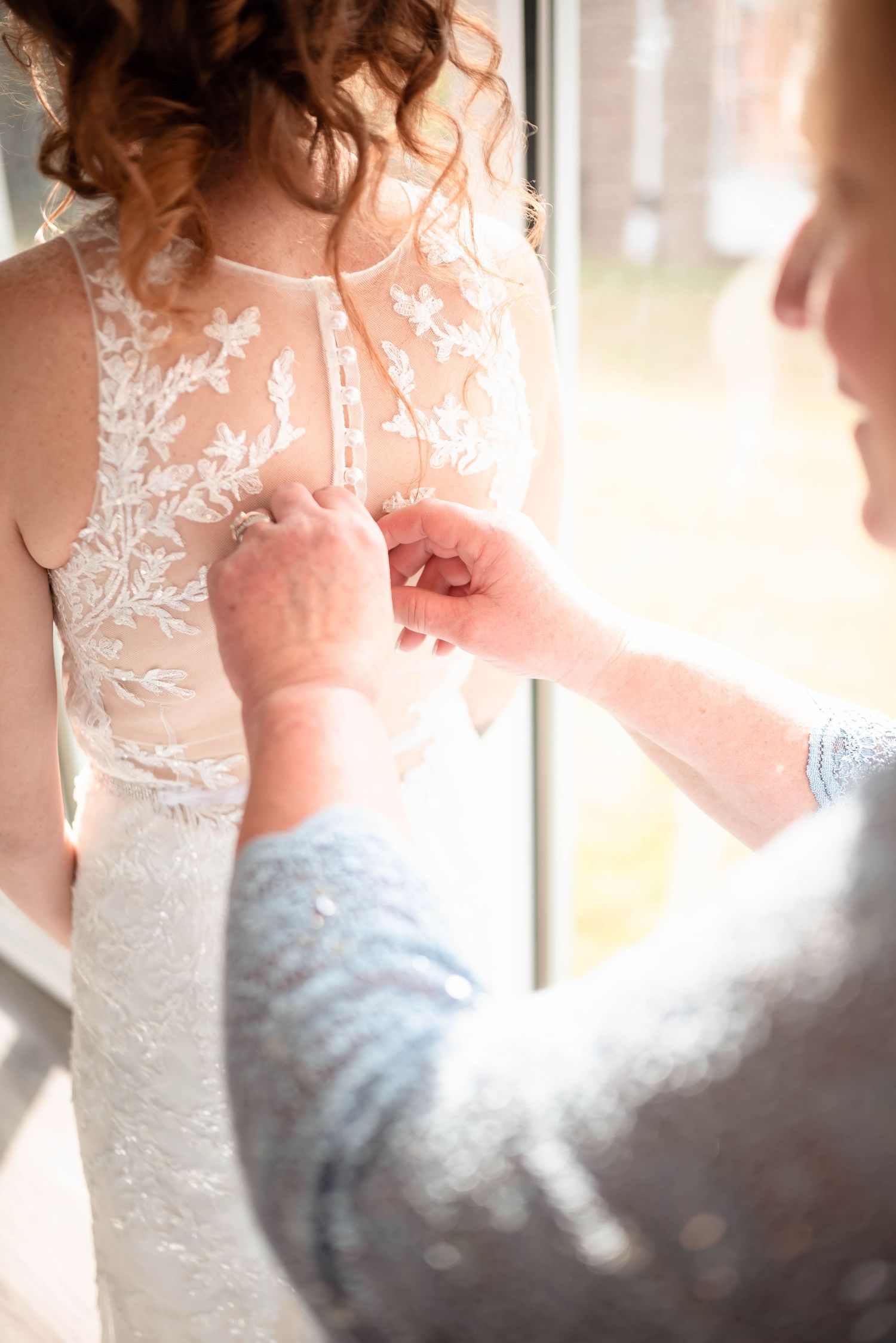 Close-up detail of delicate lace and beadwork on a white wedding dress.