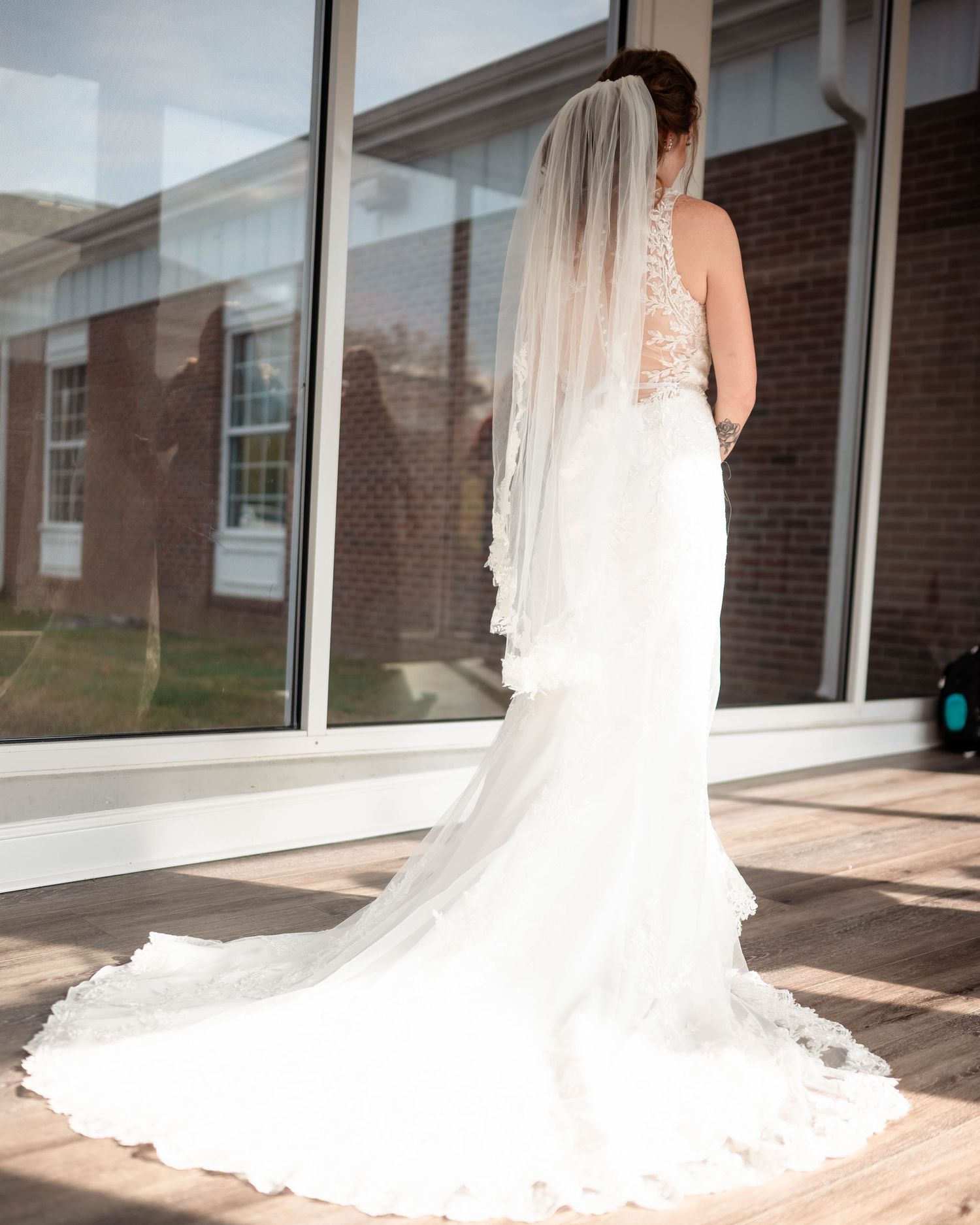 Long flowing wedding dress train displayed against natural window light in an elegant indoor setting.