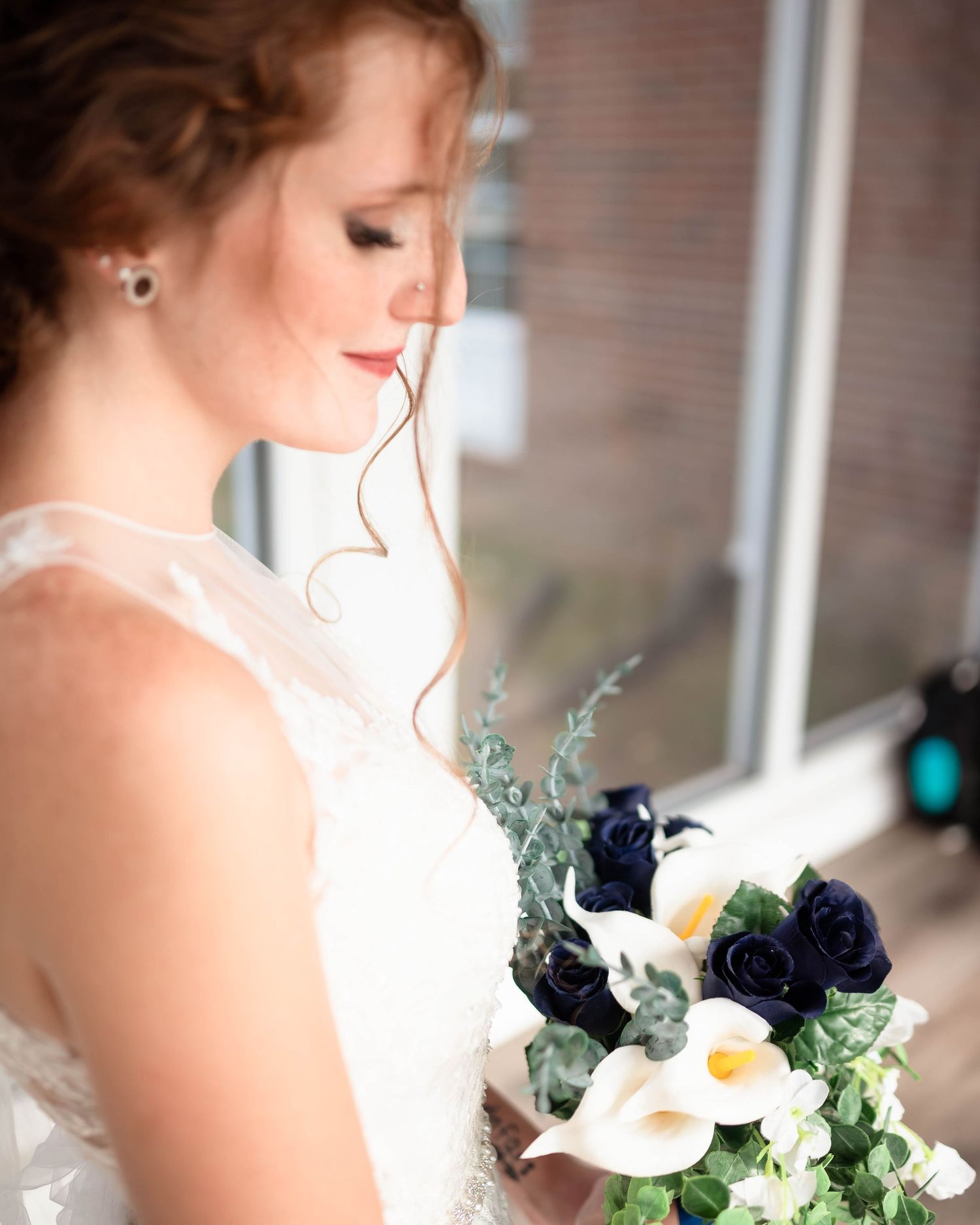 Elegant bridal portrait showing wedding dress details and bouquet with navy and white flowers.