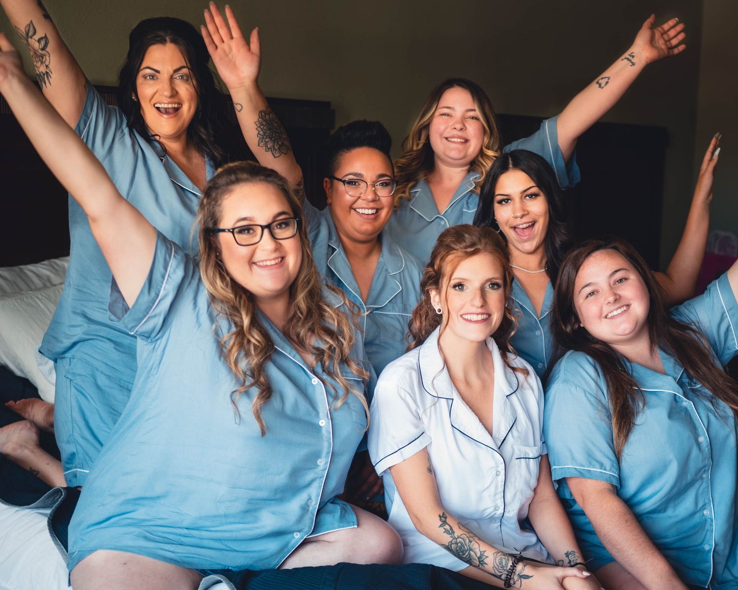 Wedding party in light blue attire celebrates with joyful expressions.