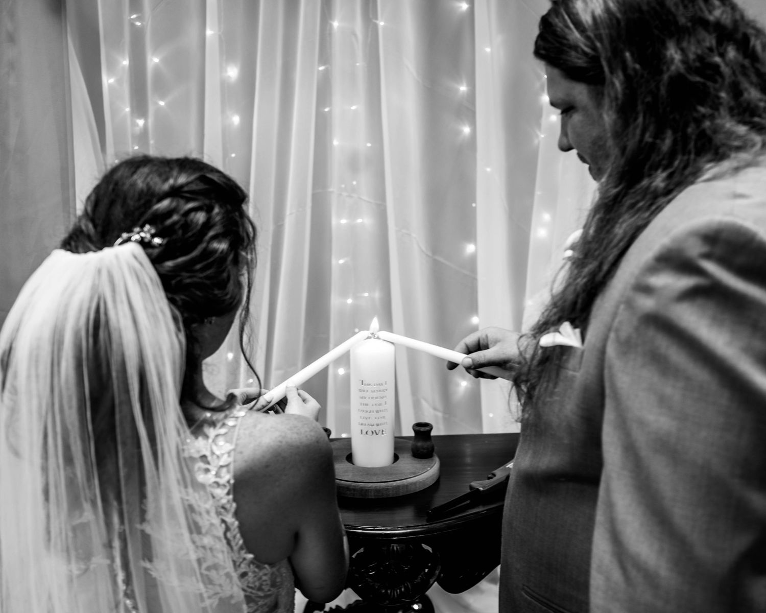 Black and white wedding ceremony moment with candle lighting.