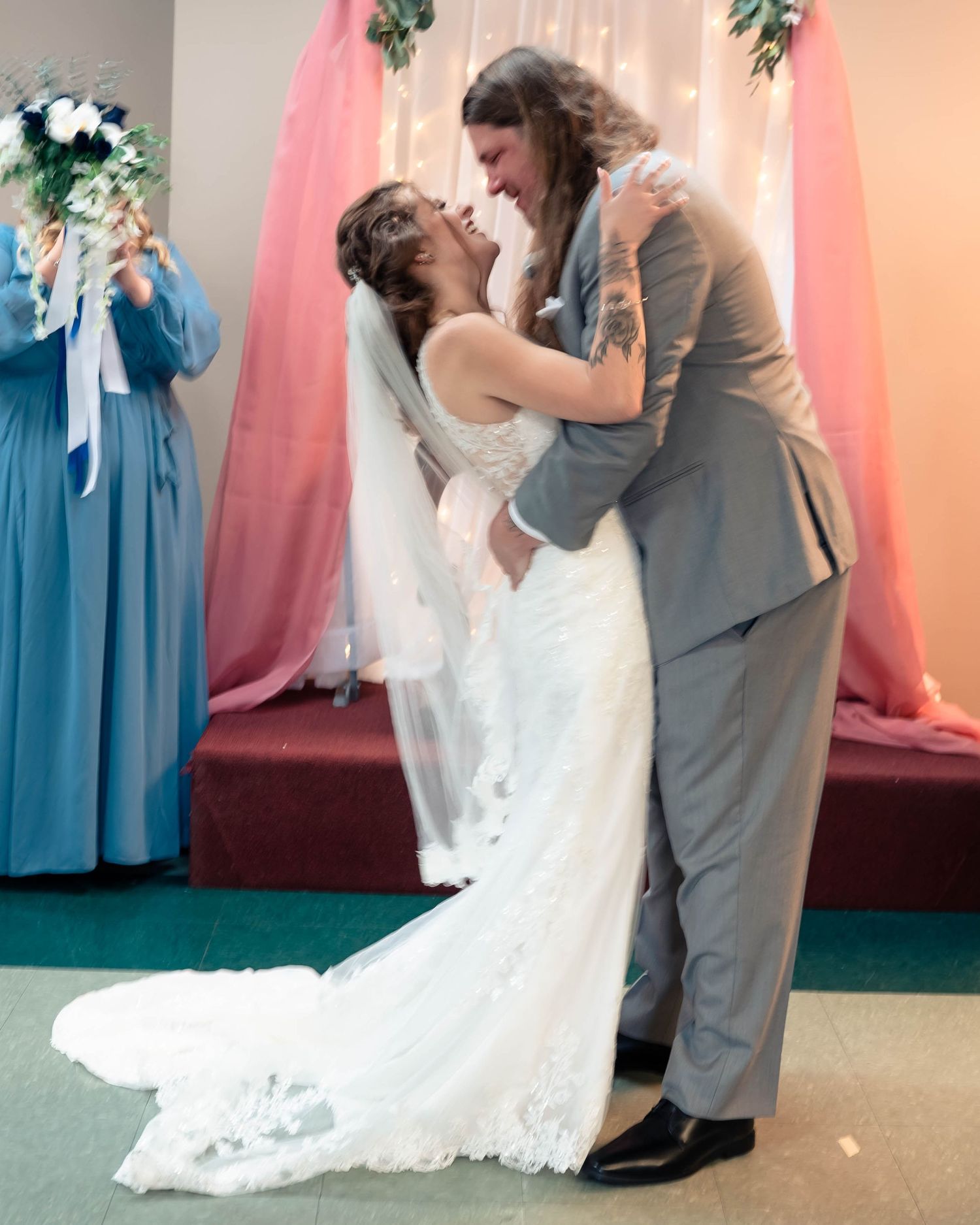 Wedding couple shares first dance while bridesmaids in blue watch.