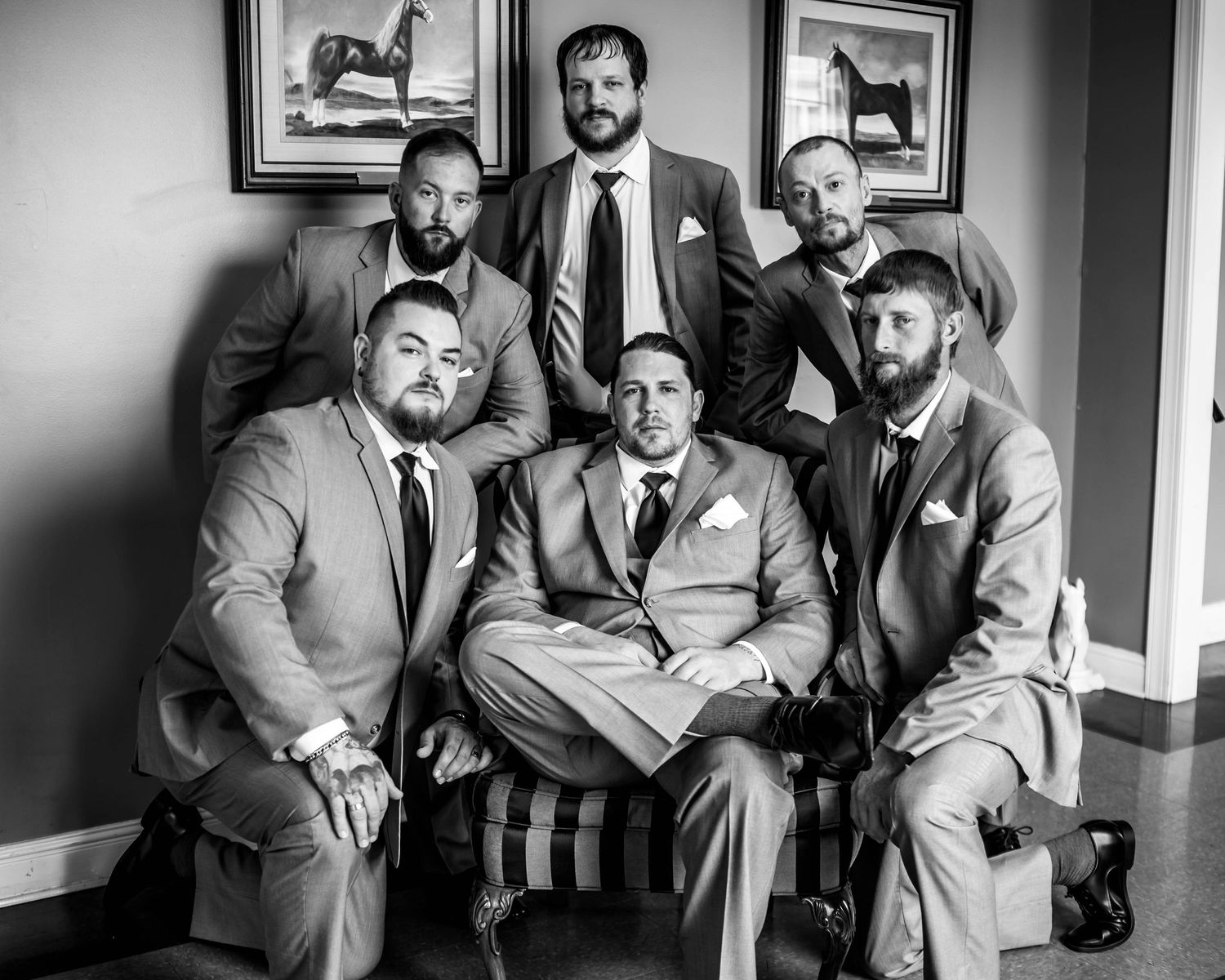 Groomsmen in grey suits pose for black and white portraits.
