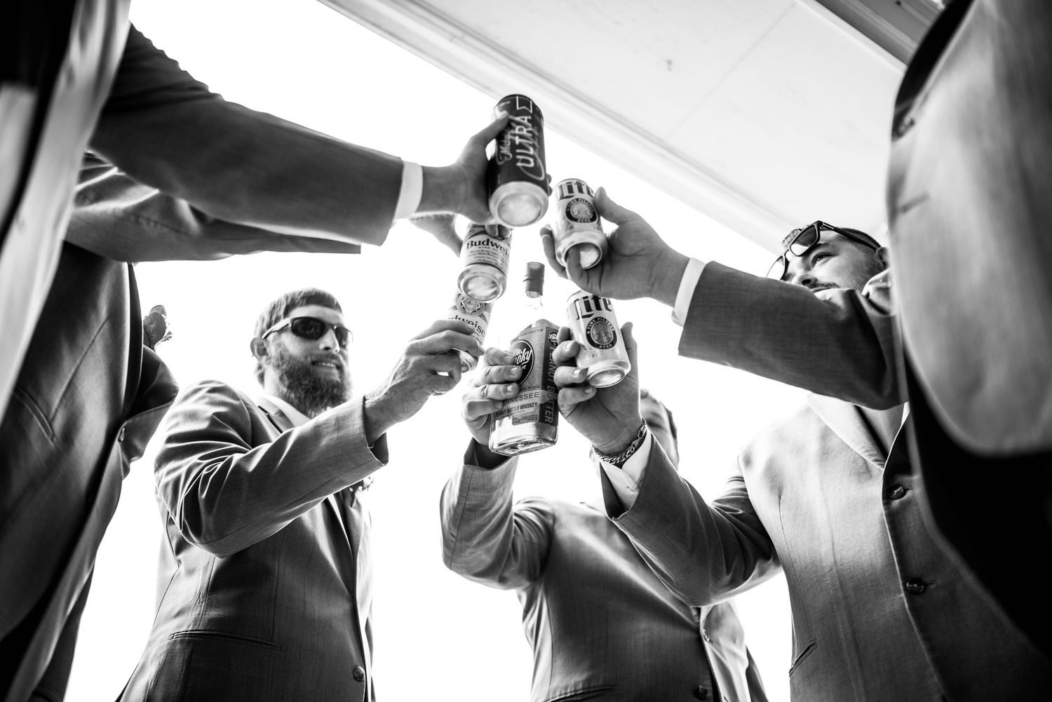 Black and white candid wedding reception photos showing guests raising glasses in celebration.