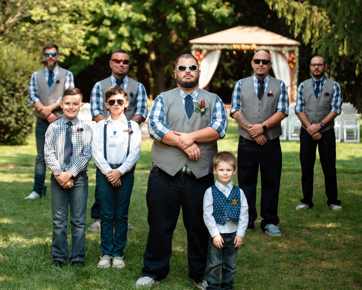 Groomsmen in coordinated blue and gray attire pose casually on grass.