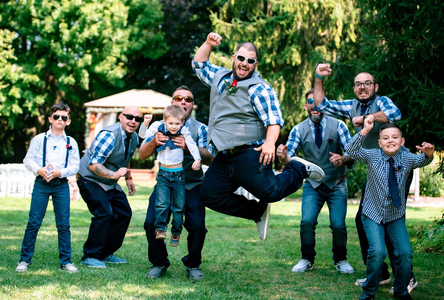 Fun group photo of wedding party members posing playfully on grass.