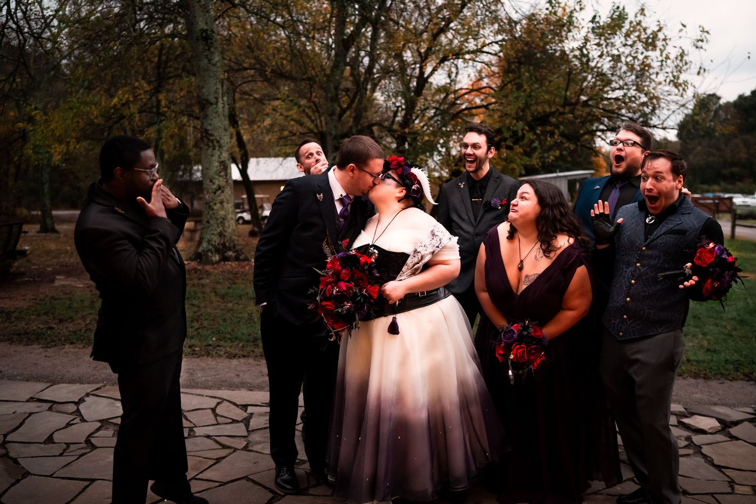 Joyful wedding party group photos in outdoor garden setting with stone pathway.