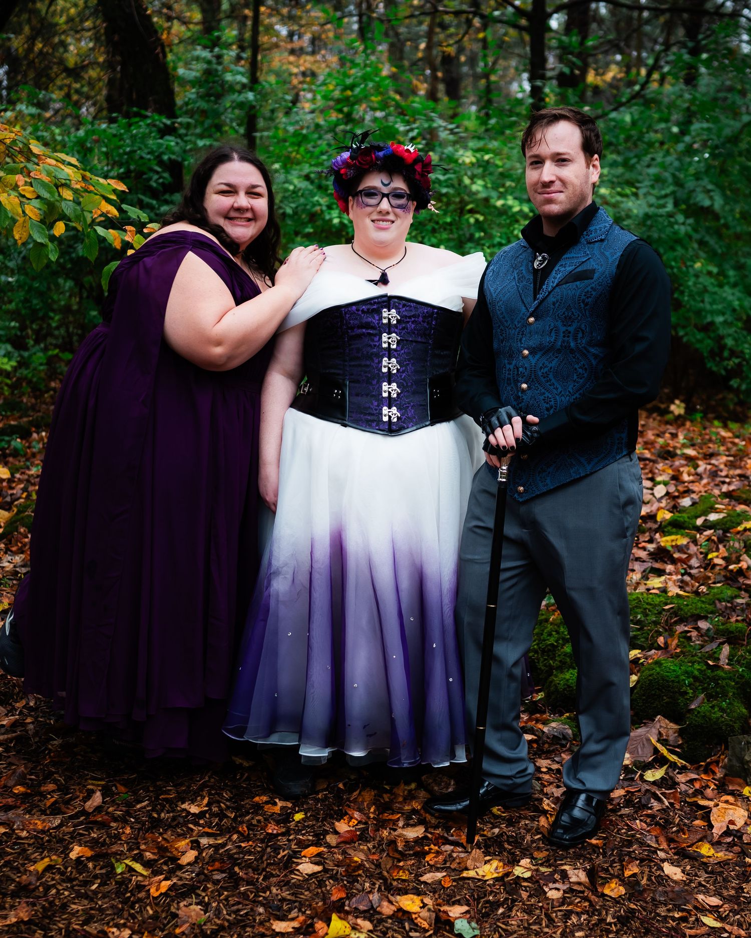 Wedding party in purple and white ombre dresses poses in autumn forest setting.