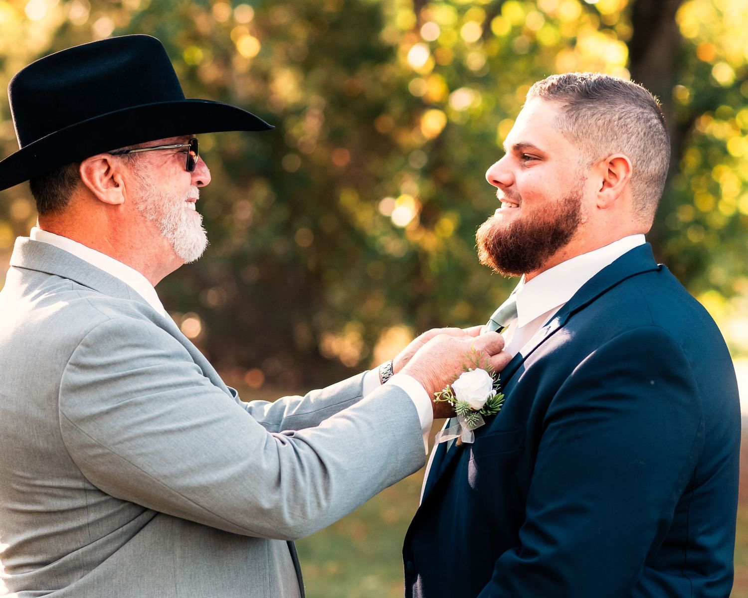 Groomsmen sharing drinks and laughs outdoors during golden hour celebration.