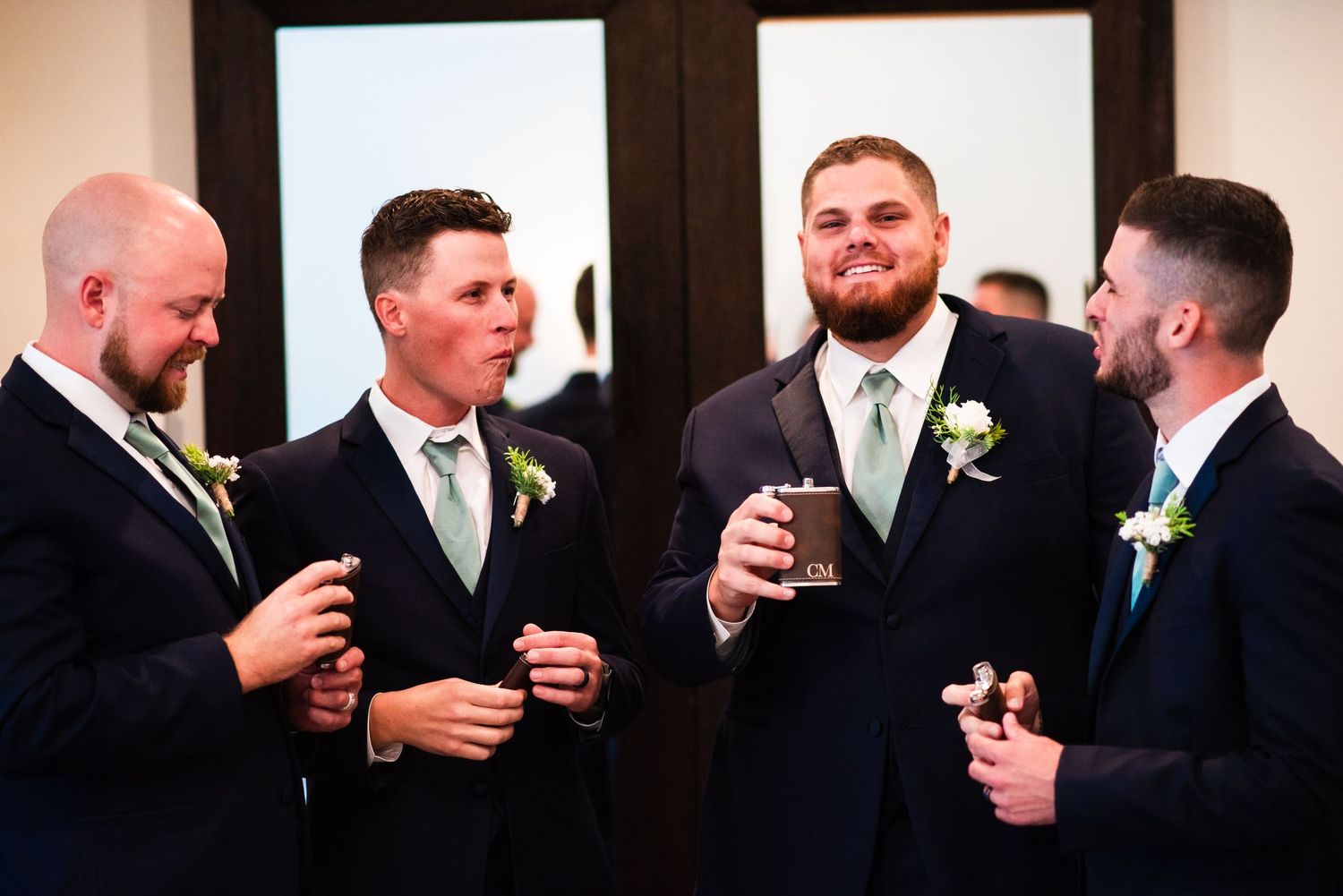 Wedding party members toasting with drinks in formal attire indoors.