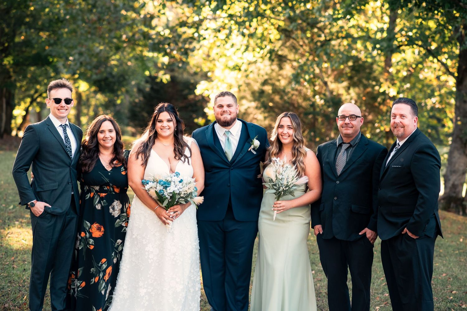 Wedding party poses together outdoors in formal attire during autumn celebration.
