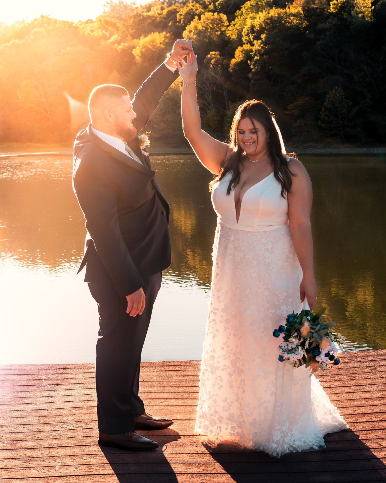 A romantic wedding photoshoot at sunset on a wooden dock by a serene lake.