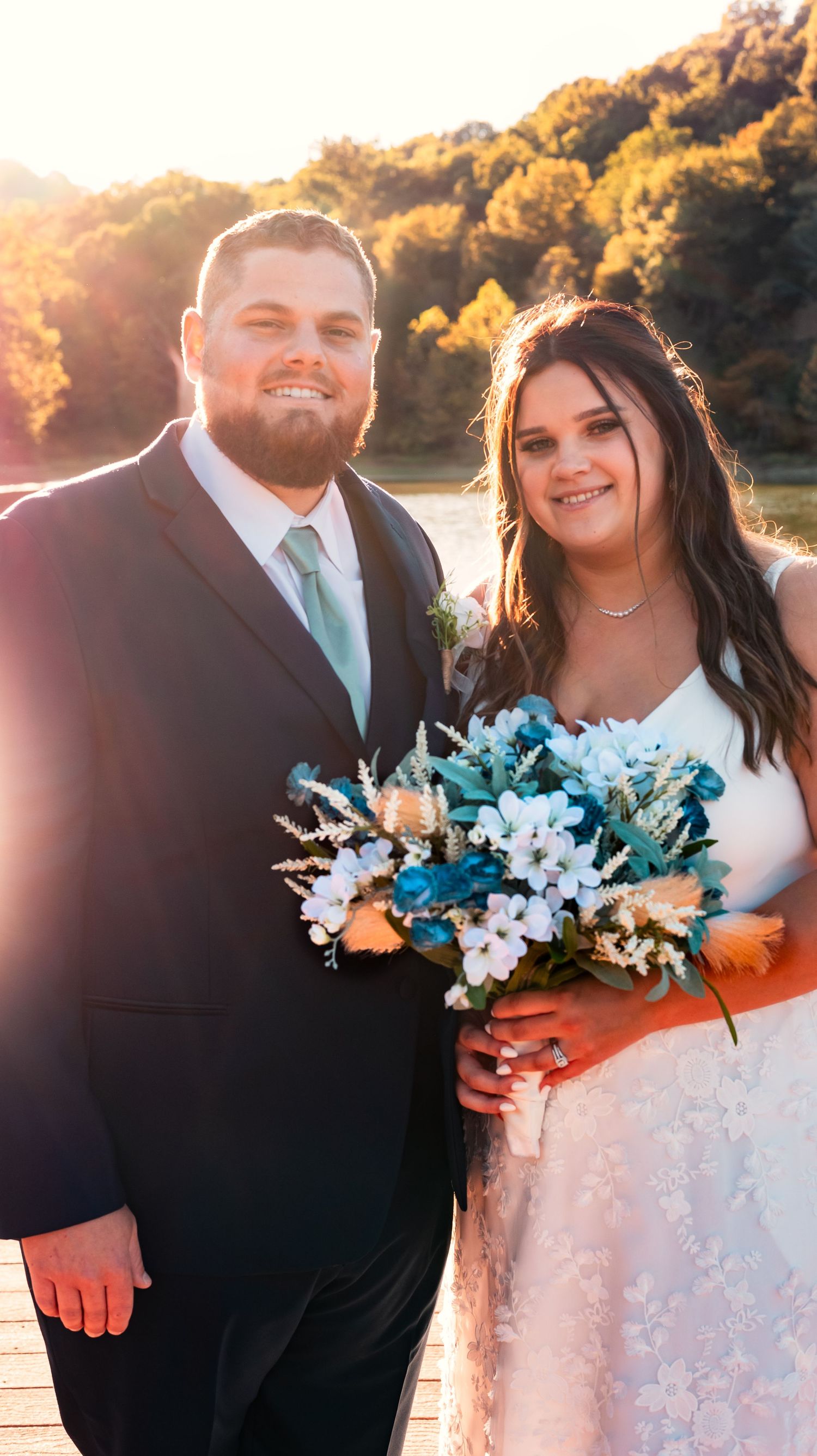 Wedding portraits with turquoise and white bouquet during golden hour by the lake.