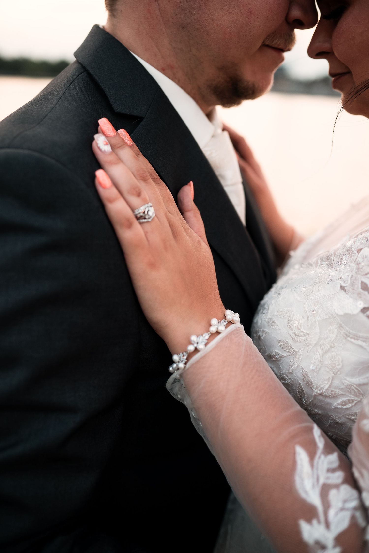Close-up details of wedding jewelry and lace as couple shares an intimate moment.