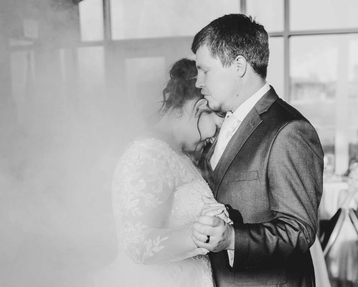 Black and white photo of couple's first dance with atmospheric fog effects.