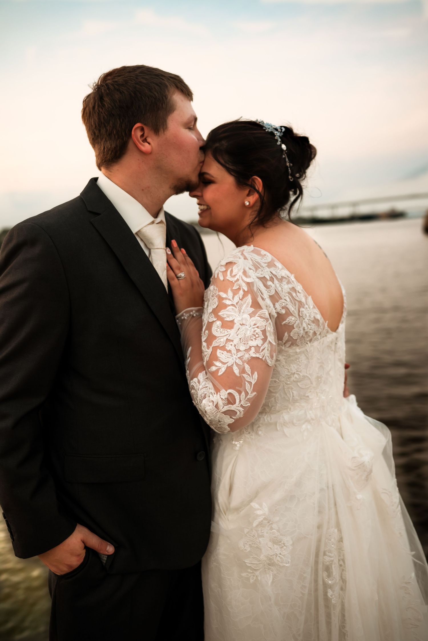 Intimate wedding couple portraits against waterfront backdrop at sunset.