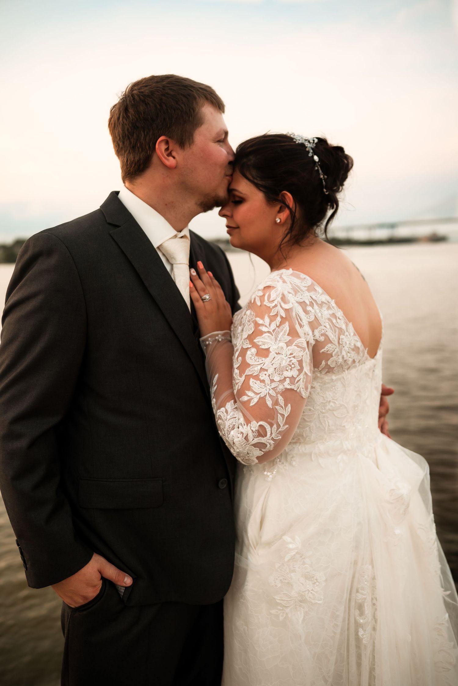Intimate wedding portraits by the water showing tender moments between newlyweds.