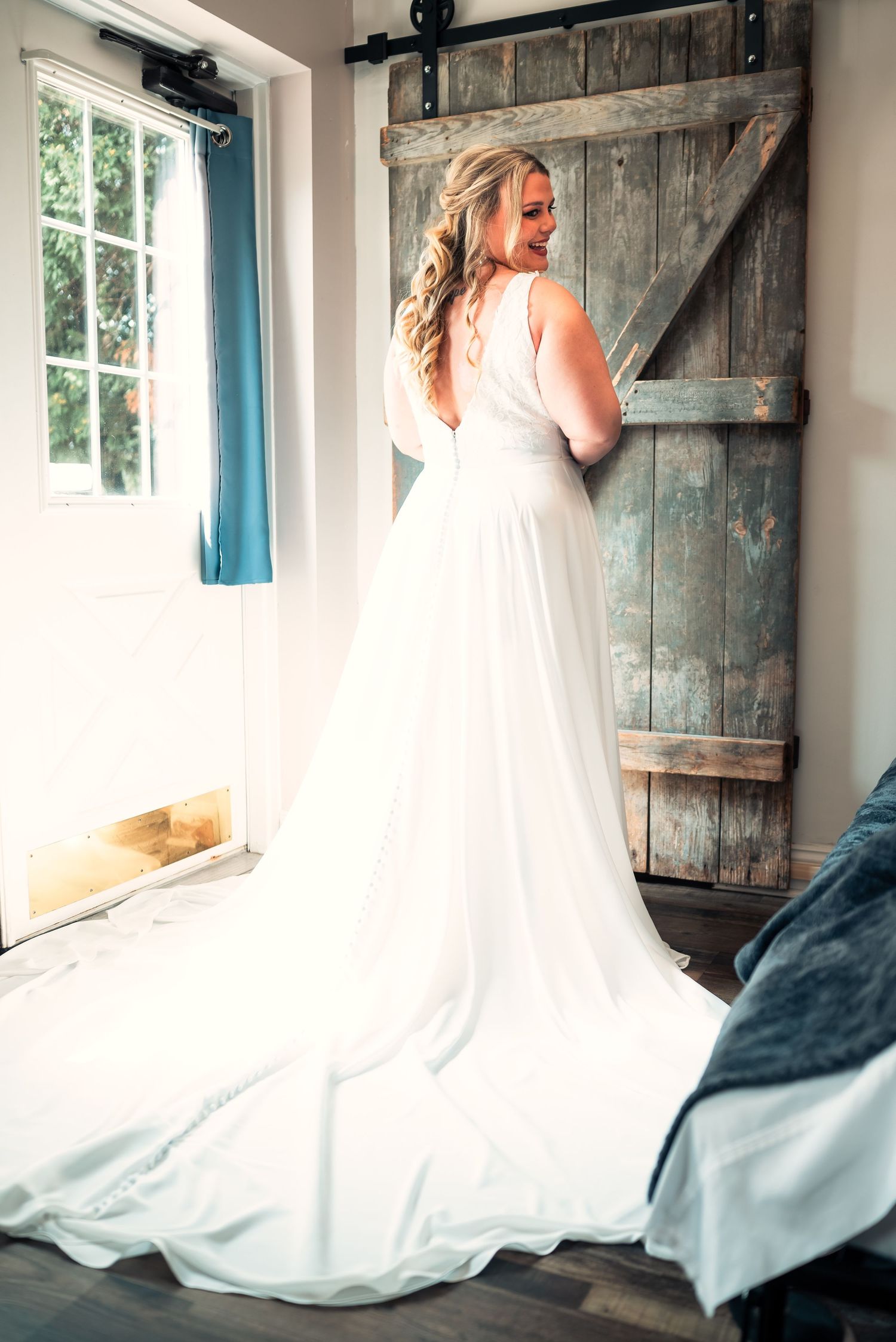 A flowing white wedding gown photographed against a rustic barn door in natural light.