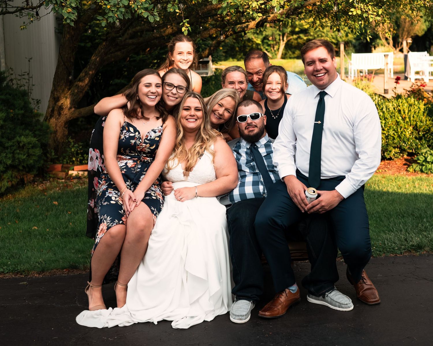 Wedding party group photo with casual poses and natural smiles in an outdoor garden setting.