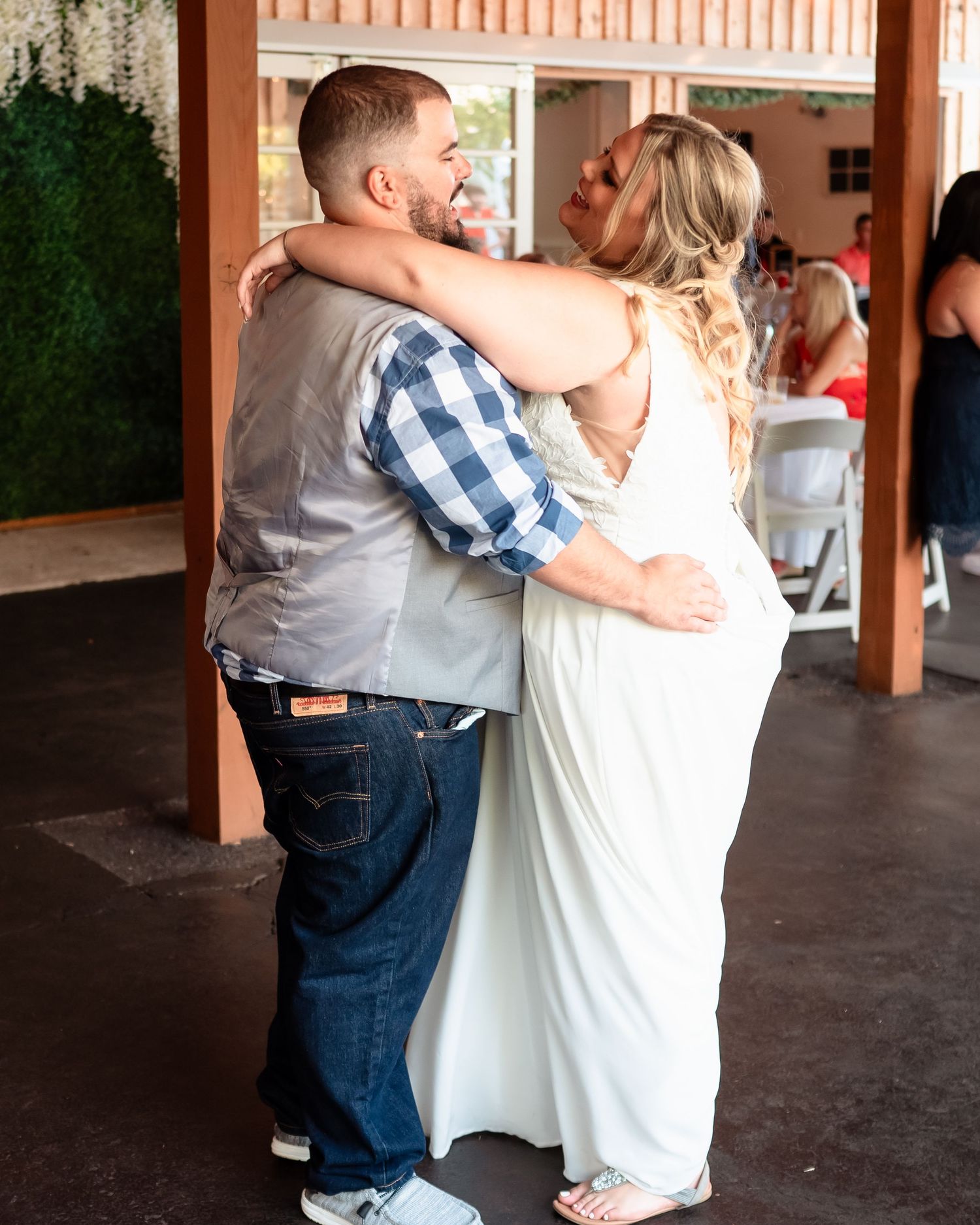 A couple shares a romantic dance moment under a covered patio during their wedding celebration.