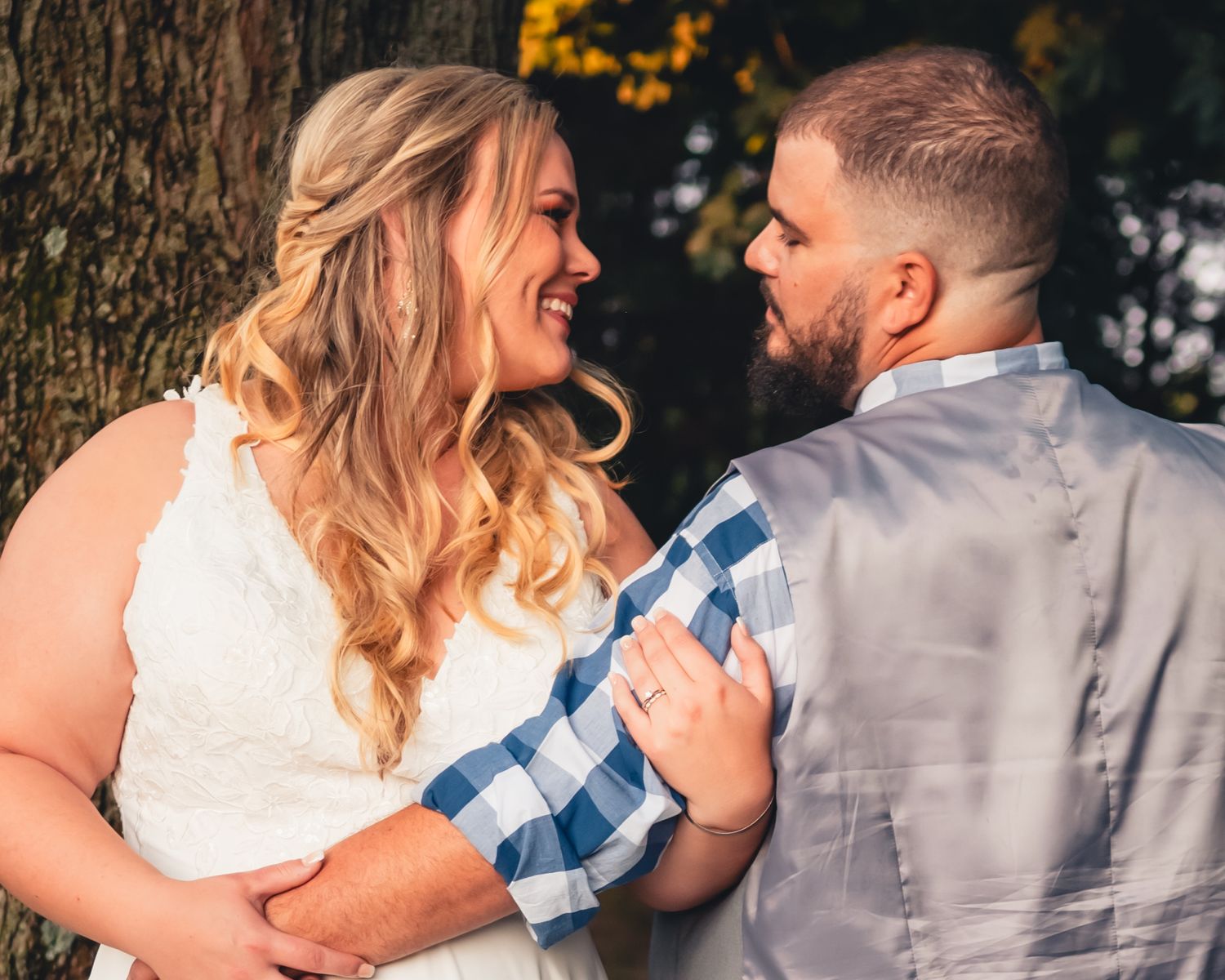A tender moment between newlyweds captured against a natural outdoor backdrop.