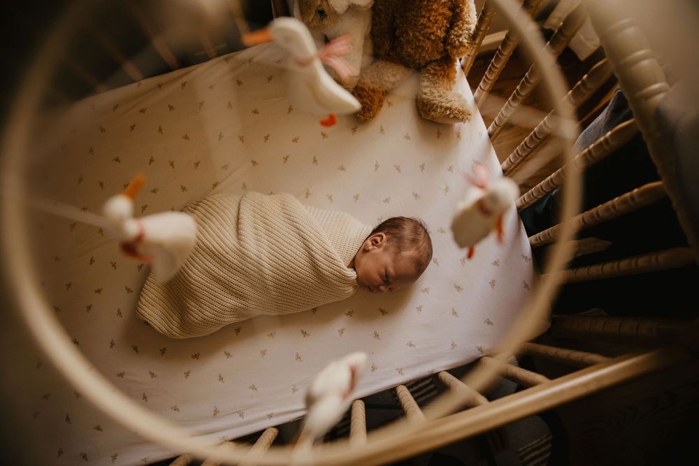 In-home newborn session with a creative aerial view through duck mobile with baby resting sweetly in his crib.