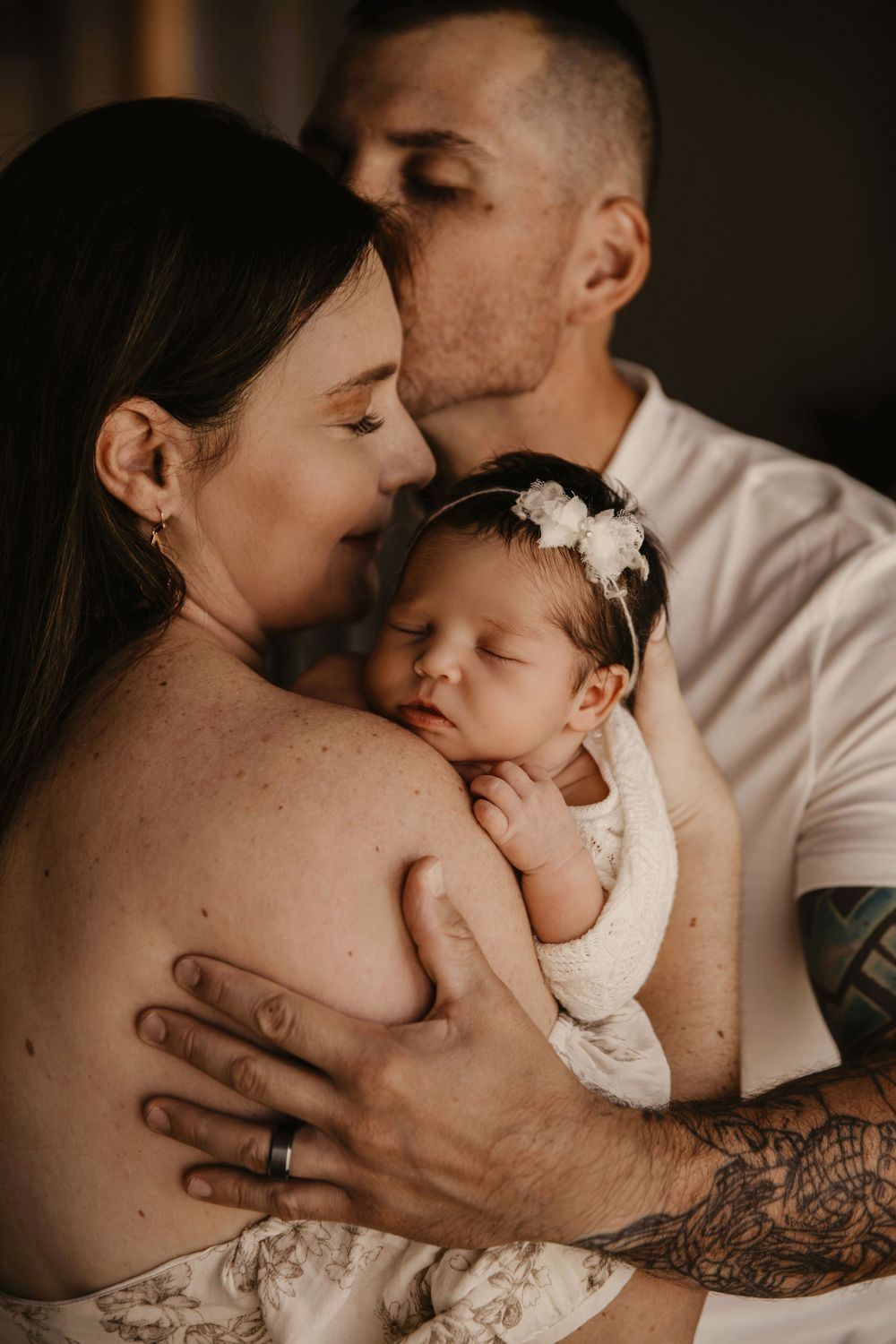 A series of intimate family photos showing tender moments between parents and their newborn baby in soft lighting.
